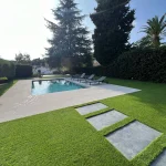 Jardín terminado en Barcelona con césped artificial Pedreña 57 alrededor de la piscina y el camino